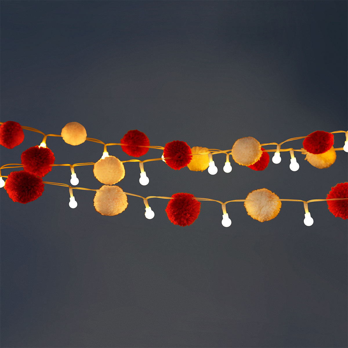 Red and white pompom string lights for home decor by Flying Tiger Copenhagen, featuring colorful, festive lighting for interior spaces.