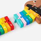Wooden sausage dog alphabet puzzle toy by Flying Tiger Copenhagen with colorful letter pieces on a wooden board.