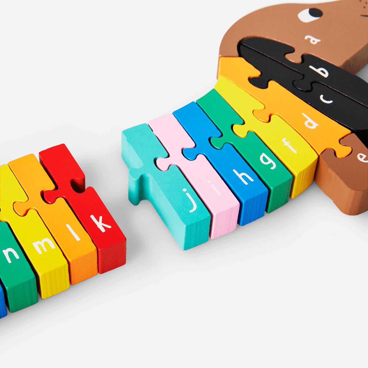 Wooden sausage dog alphabet puzzle toy by Flying Tiger Copenhagen with colorful letter pieces on a wooden board.