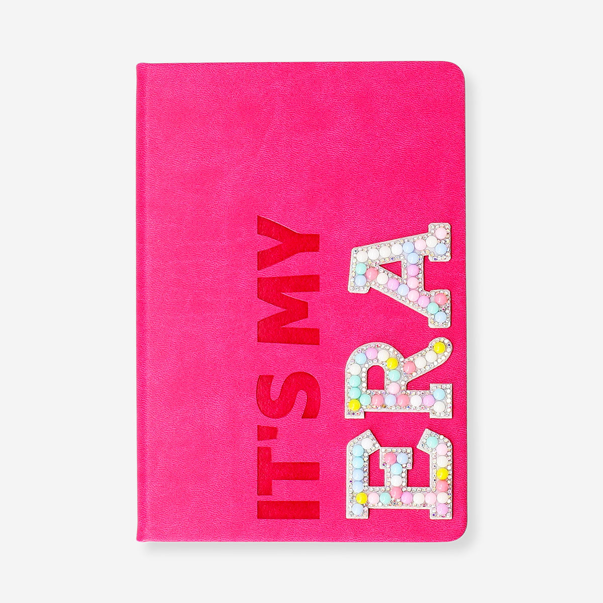 Pink A5 office notebook with playful pom poms from Flying Tiger Copenhagen, featuring a soft cover and spiral binding.