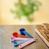 Flying Tiger Copenhagen Designer Collection measuring spoons set of 4, colorful kitchen tools arranged on a white background.