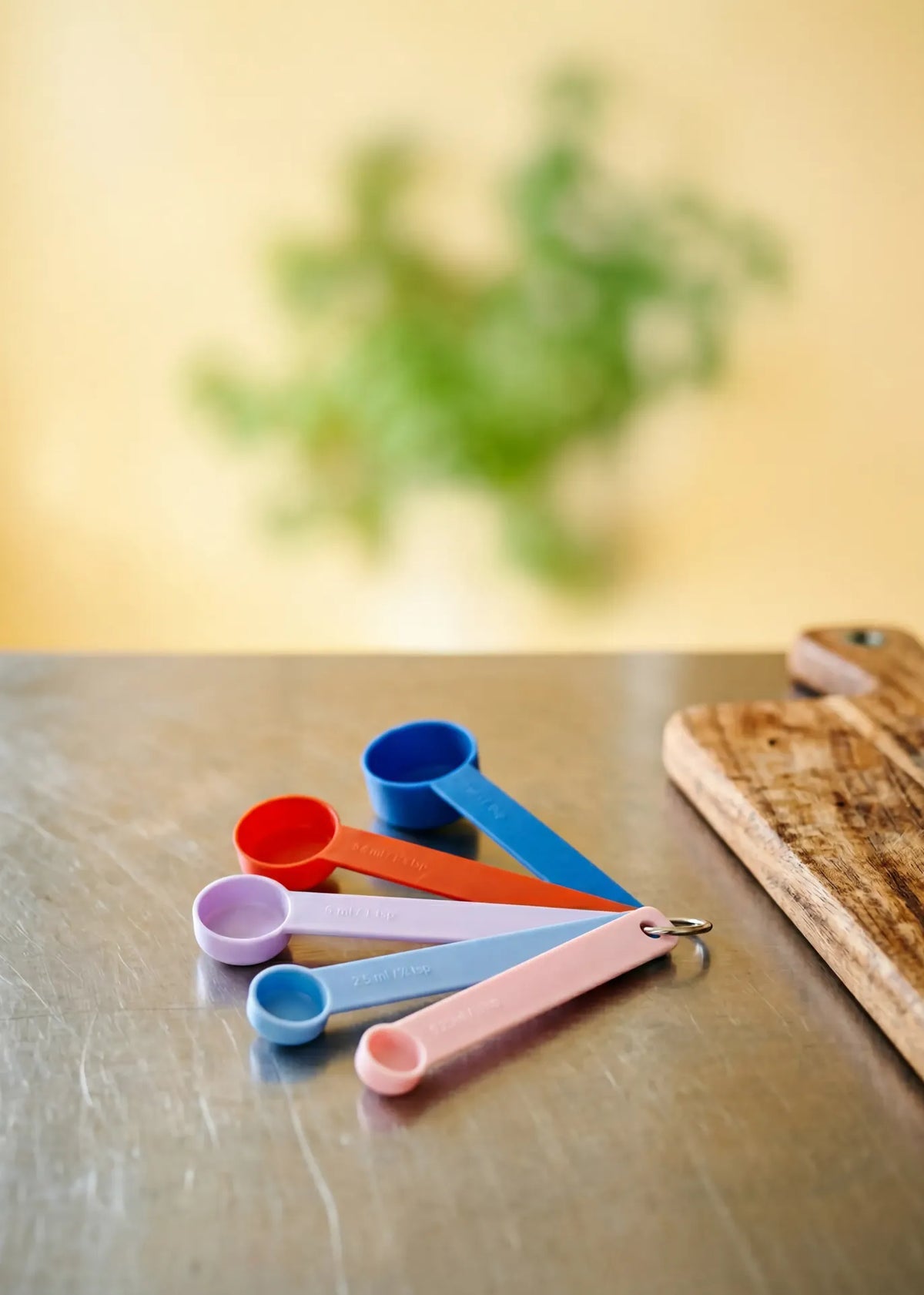Flying Tiger Copenhagen Designer Collection measuring spoons set of 4, colorful kitchen tools arranged on a white background.