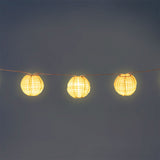 Outdoor string lights with striped fabric ball covers by Flying Tiger Copenhagen, perfect for garden or patio decor.