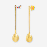 Two gold dessert spoons with tropical flower decorations, Flying Tiger Copenhagen kitchenware, showing intricate floral details.