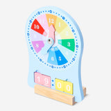 Wooden teaching clock toy by Flying Tiger Copenhagen, featuring movable hour and minute hands on a colorful educational clock face.