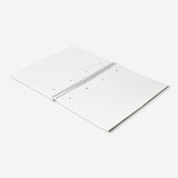A4 spiral-bound lined notebook with a craft paper cover by Flying Tiger Copenhagen, open to show lined pages inside.