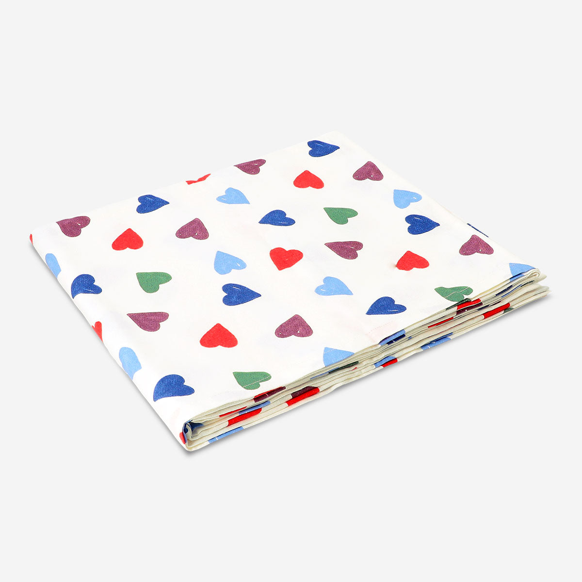 Heart-patterned tablecloth from Flying Tiger Copenhagen, 140x220 cm, showing a cozy home dining setup with colorful heart designs.