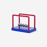 Blue and red Newton's cradle gadget by Flying Tiger Copenhagen showing swinging metal balls.