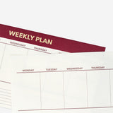 Red weekly desk planner from Flying Tiger Copenhagen, featuring organized pages for scheduling and note-taking.