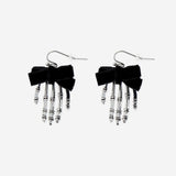 Textile skeleton hands earrings with detailed black and white design, hanging from silver hooks, by Flying Tiger Copenhagen.