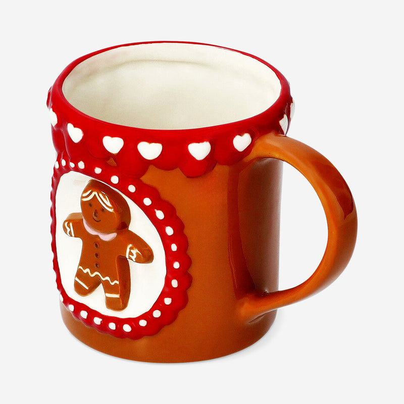 Brown and red ceramic mug featuring a raised gingerbread man design within a white and red scalloped frame, decorated with small white hearts along the rim, displayed on a plain white background.