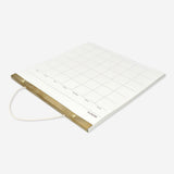 Hanging monthly office planner by Flying Tiger Copenhagen with calendar pages and colorful design for organized scheduling.